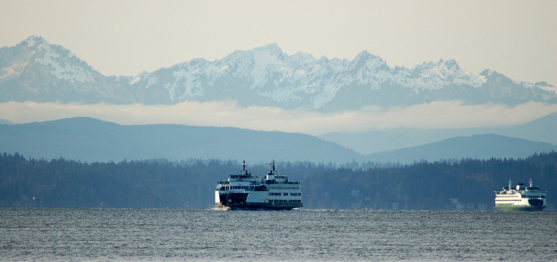 Two Washington State ferries crossing Puget Sound with the Olympic Mountains behind them